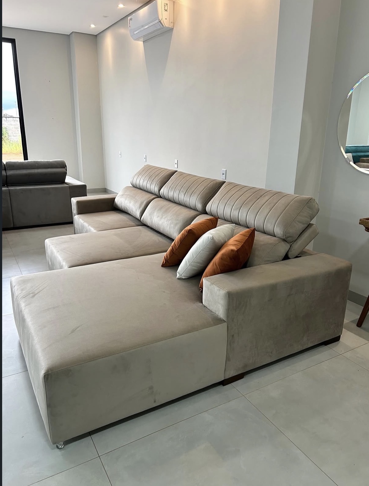 Sofá bege com chaise e almofadas terrosas