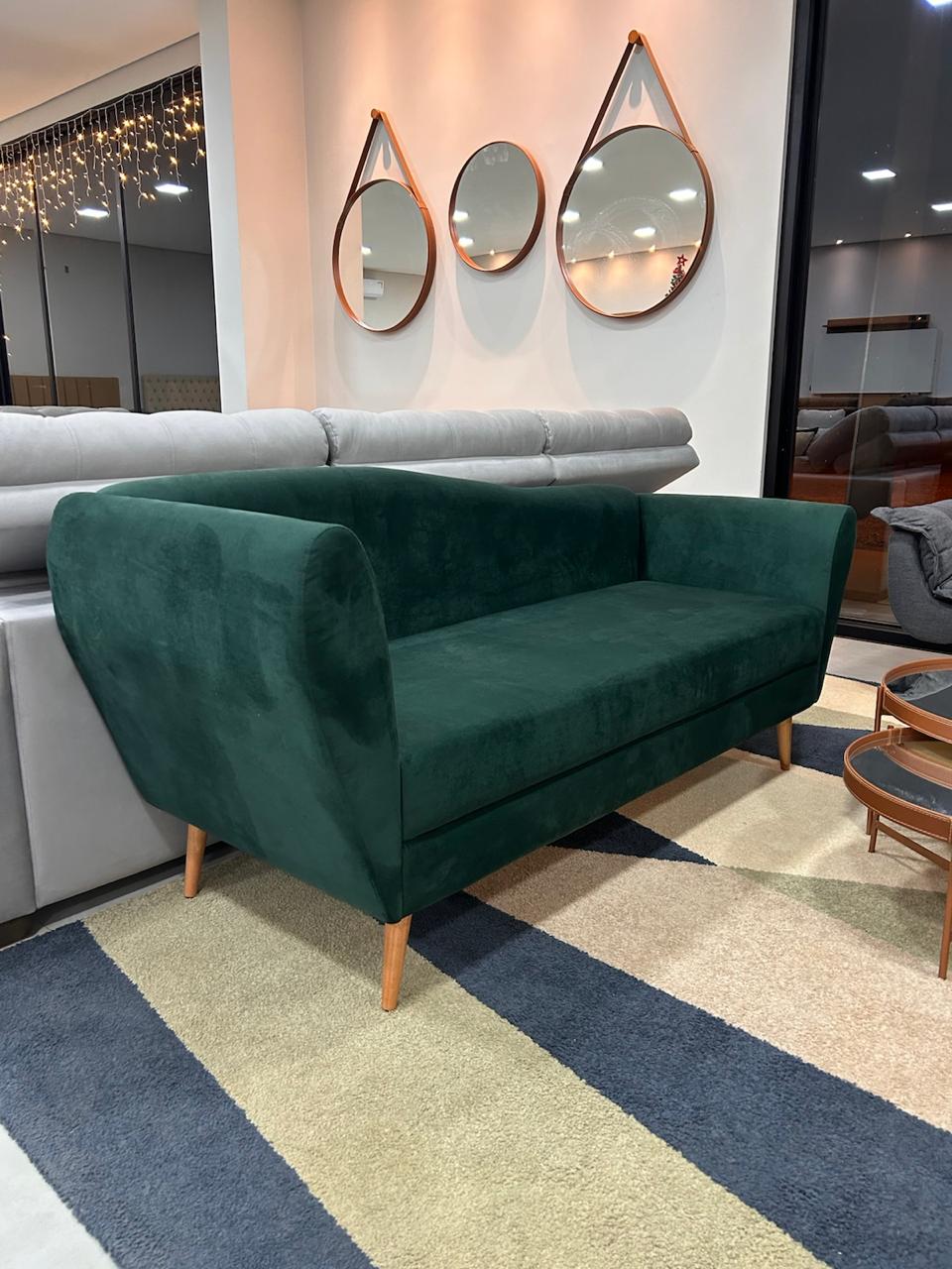 Sofá verde com pés de madeira no showroom